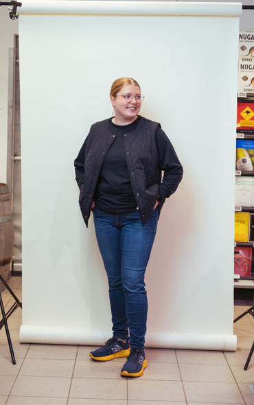Ung kvinde med briller står foran hvid baggrund i fotostudie