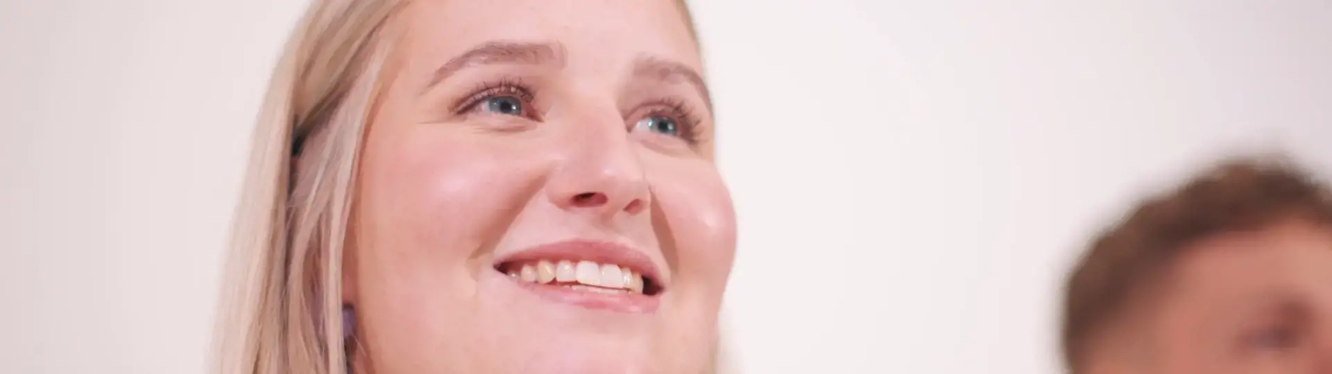 Smilende ung kvinde med lyst hår ser opad